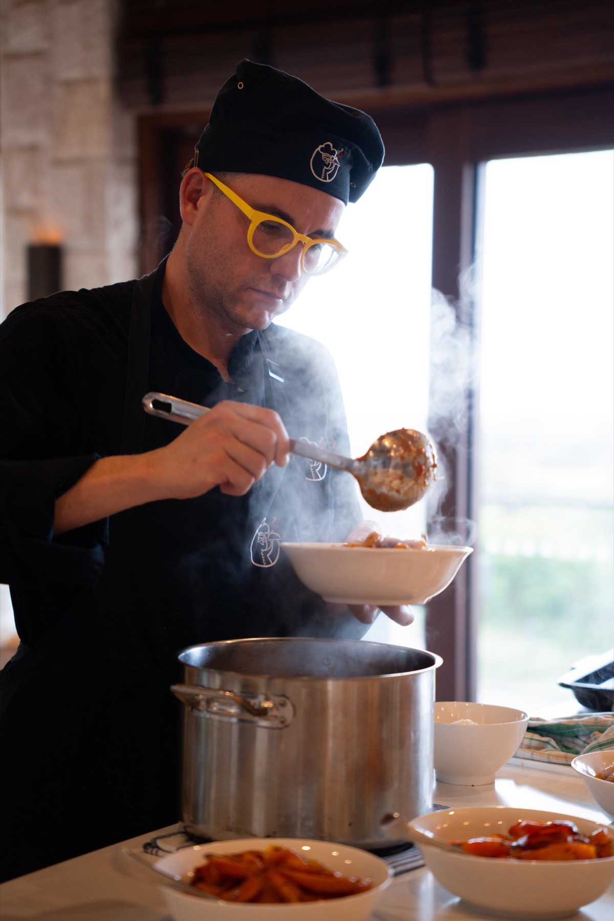 Chef Michele Guarneri ladling a fresh Italian dish in the kitchen